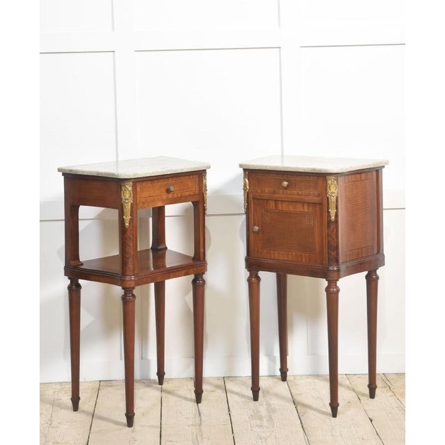 Pair of French Neoclassical gilt metal mounted bedside cabinets with shaped marble tops, above short drawer one fitted...