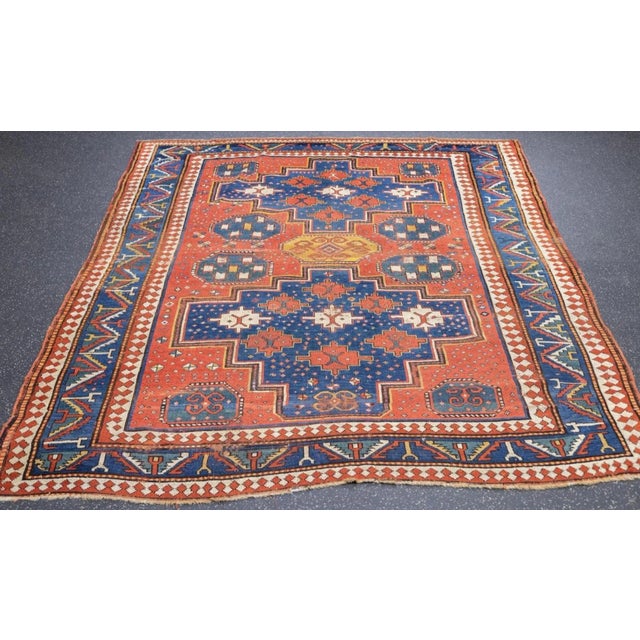 A variant on the "Three Medallion" Kazak type, with a madder field supporting two abashed, broadly stepped blue...