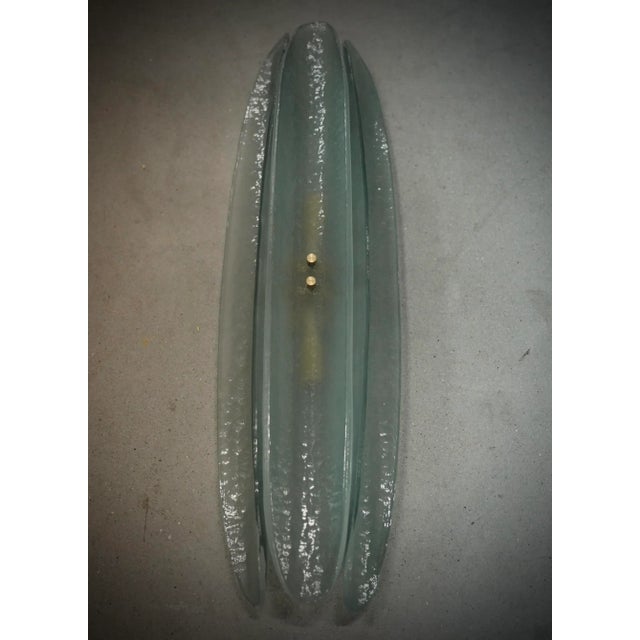 Very original Murano glass wall lamp with a very elongated design of the glass half shell and a unique light green color....