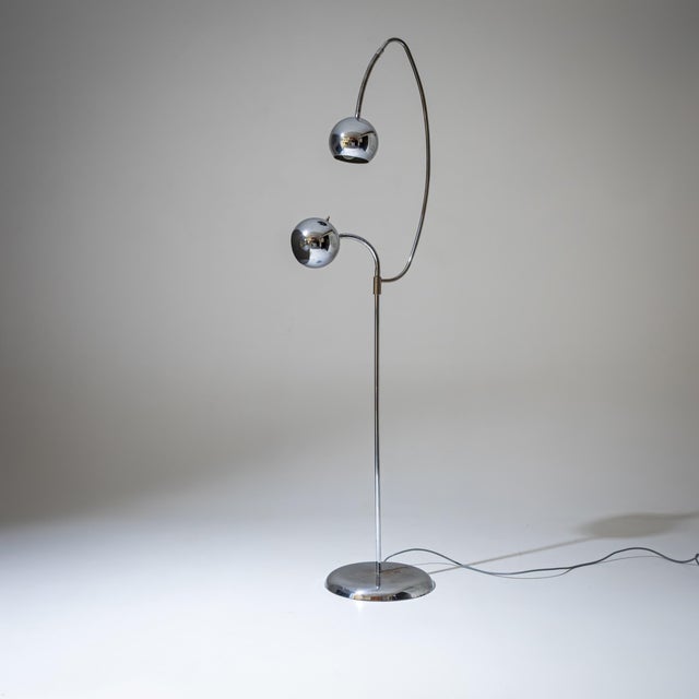 Chrome-plated floor lamp with a circular base and slender stems with adjustable necks and two round shades. The lights can...