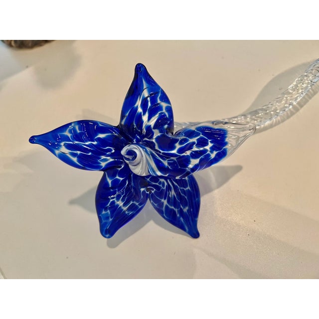 Beautiful blown glass art of a flower measuring 14.5” long and the span of the pedals are 5” . The stem is clear and the...