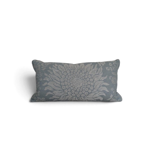 A decorative pair of banquette pillows featuring an oversized floral sunflower motif in soft blue-gray and warm neutral...