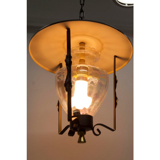 1960s wrought iron lantern-style ceiling light. Clear glass with a pearly sheen. Sturdy black frame with gold accents. All...