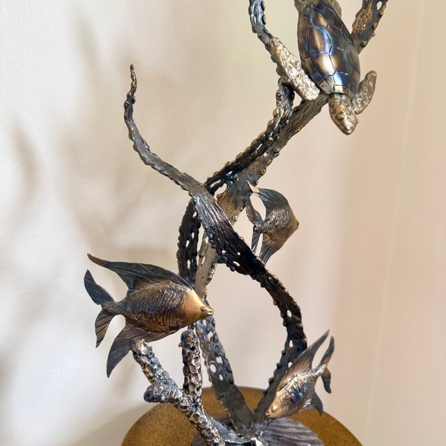 Graceful ocean-inspired metal sculpture with sea turtle, tropical fish, and flowing reef forms in a dramatic vertical...