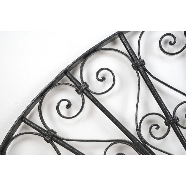 Reclaimed French style arch shaped transom made of wrought iron with a black exterior. It features a semi circular design...