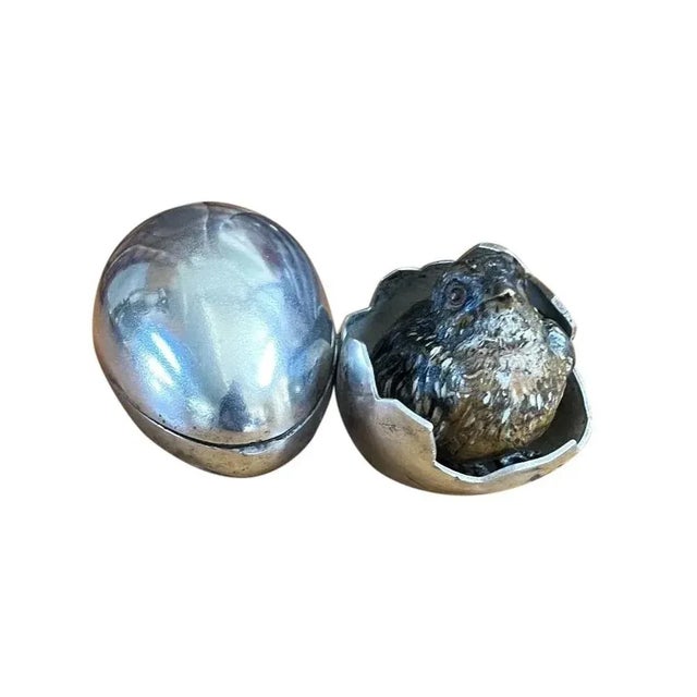 An antique cold painted inkwell featuring a small bird in a silver metal eggshell. The shell with cracked design is...