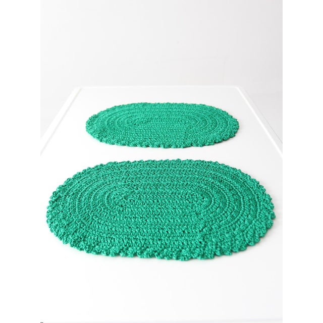 This pair of vintage crocheted placemats features a rich green hue and soft oval shape with a scalloped edge, crafted in a...