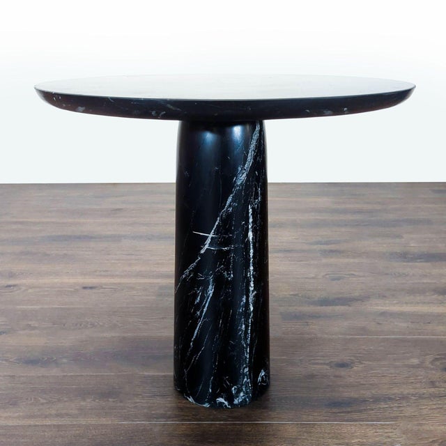 Honed black marble bistro table by Barcelona-based Mermelada Estudio is a sculptural work of art. It has a tapered...