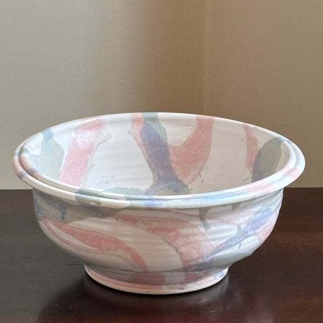 Offering a late-20th / early-21st century artisanal pottery bowl. This handcrafted bowl features a soft pastel color...