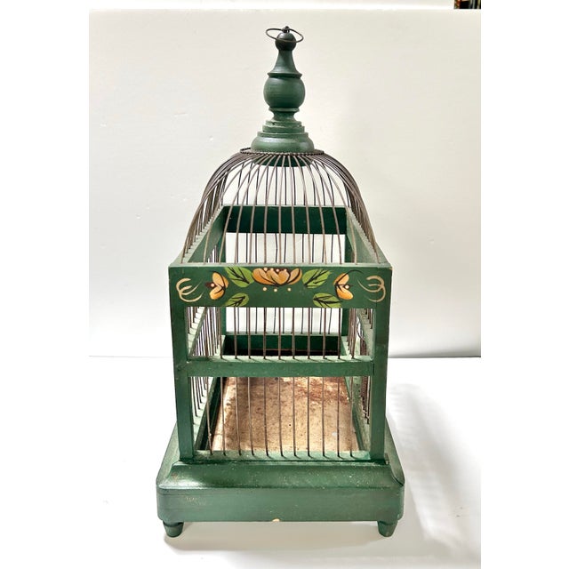 A beautiful hand-painted wooden and wire birdcage. It has a domed top and a spring-loaded door that closes itself. The...