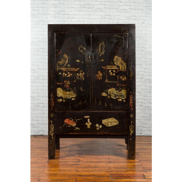 A Qing dynasty two-door elmwood cabinet from the 19th century, with original black lacquer and hand-painted decor. Created...