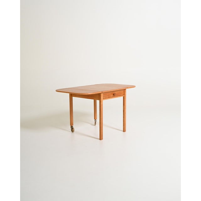 Oak table with drawer, two drop-leaf extension leaves, and two legs with casters. "Trissan" model by Sven Engström &...