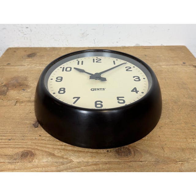 Wall clock produced by Gents of Leicester in England during the 1950s. It features a brown bakelite frame, an iron dial,...