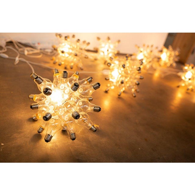 26 light-bulbs are stuck together like a cluster of bubbles. One light-bulb is connected to the power-source and burns....