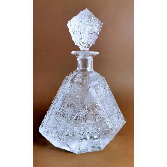 Hand-cut and ground crystal bottle; its shape is unusual and peculiar, even the stopper echoes the lines of the bottle; an...