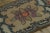 This antique 2x4 hooked rug, circa 1920–1929, displays a floral medallion framed by scrolling foliate motifs and stylized...