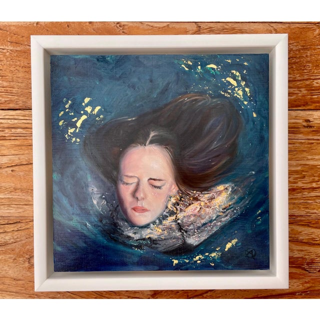 This artwork depicts a serene figure submerged in deep blue waters, her eyes gently closed, evoking a sense of tranquility...