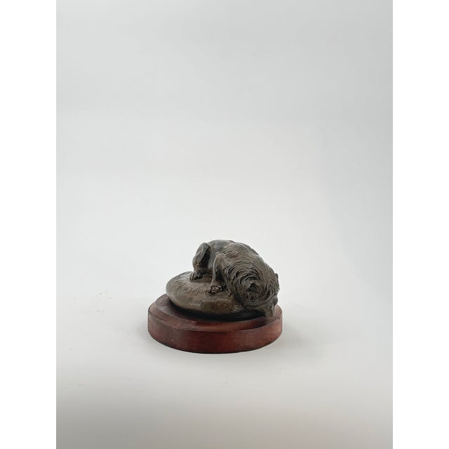 This striking bronze sculpture captures a powerful lion poised at a watering hole, his muscular form extending over the...