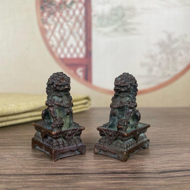 This charming pair of miniature bronze guardian lions brings a touch of history to any desk or shelf. Each lion is finely...