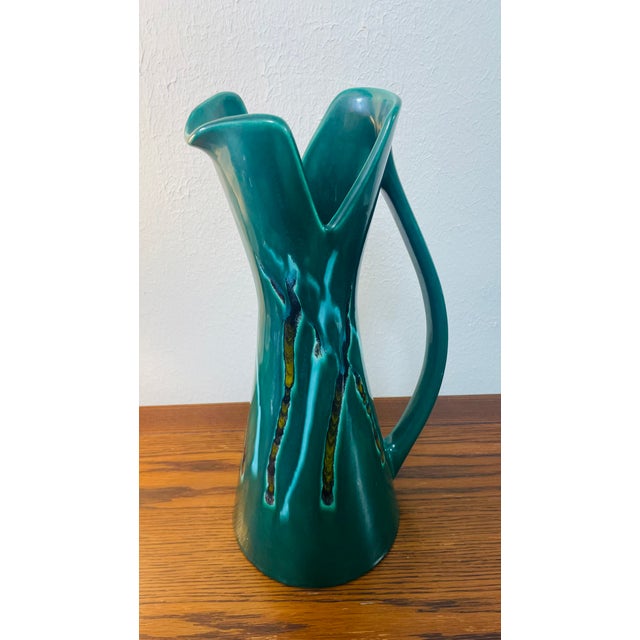 Make a bold statement with this stunning Mid-Century Modern art pottery pitcher featuring a dramatic sculptural silhouette...