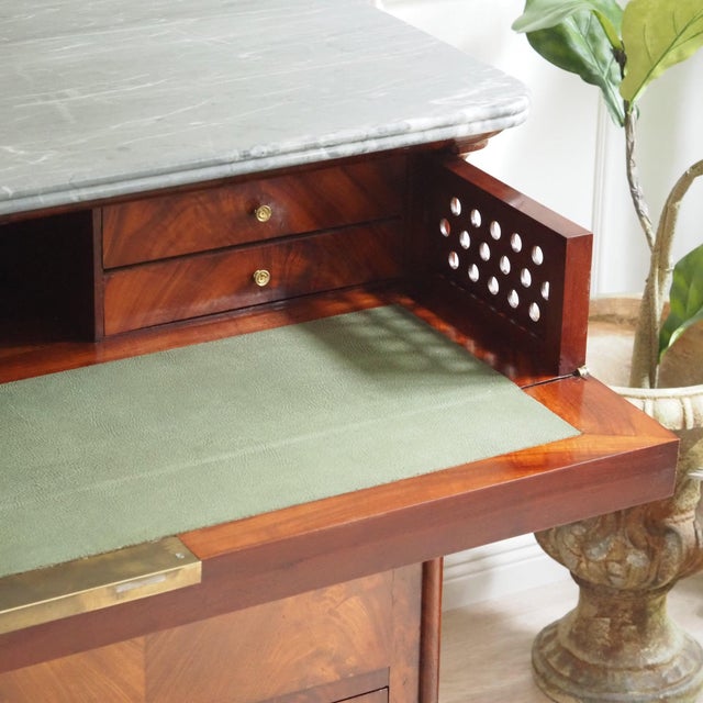 A historic secretary desk dating from around 1840–1860, featuring an elegantly veined gray marble top, flame-like mahogany...