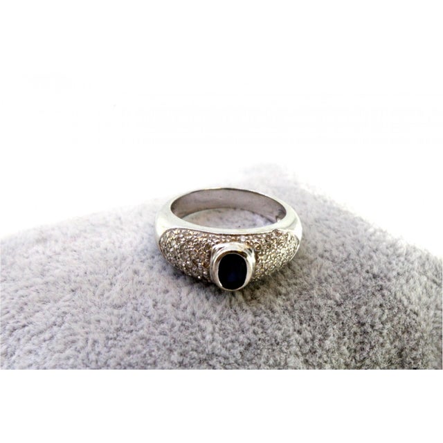 White gold ring with brilliant-cut diamonds (64) and an oval-shaped Australian sapphire in the center. Metal: Gold....