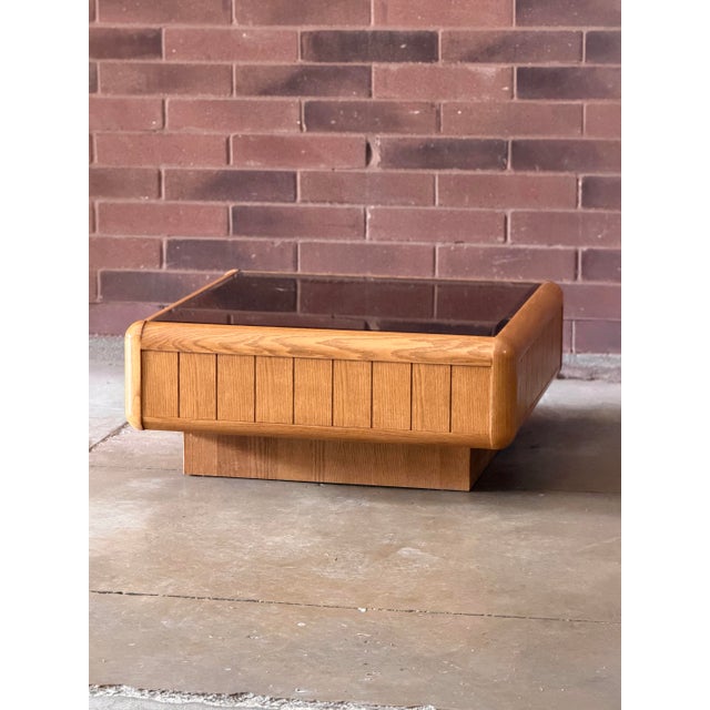 A distinctive vintage California Modern coffee table, circa late 1970s to early 1980s, featuring a warm golden oak frame...