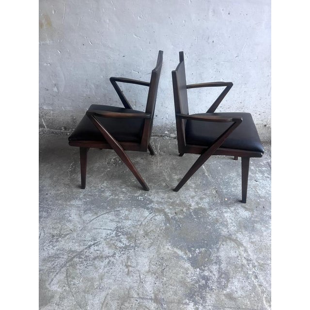Striking pair of mid-century armchairs dating from the 1950s–1960s. The chairs feature sculptural dark-stained wooden...
