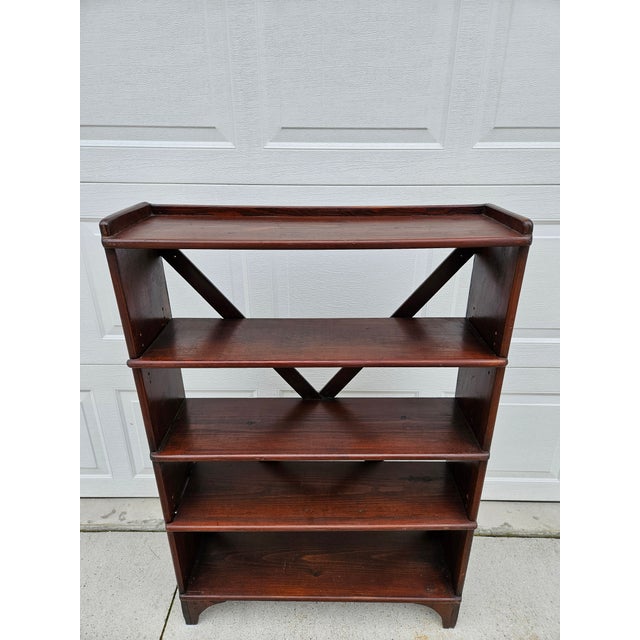 This antique rustic looking bookcase or etagere has three fixed shelves and two adjustable shelves. The shelves are braced...