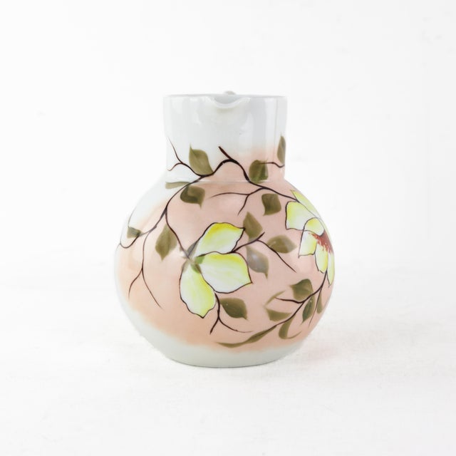This charming vintage porcelain pitcher features bold yellow blossoms beautifully hand-painted against a soft peach...