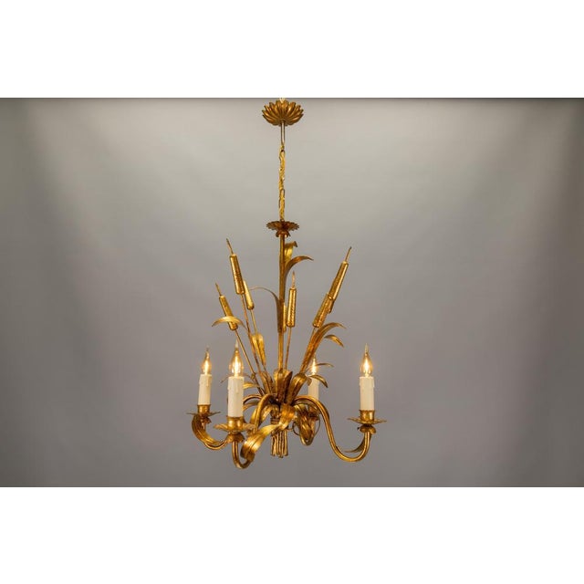 Mid-Century Hollywood Regency four-light chandelier crafted in gilt metal, featuring sculptural cattail (reed) motifs....