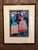 Framed art print titled "Under the Moon" by Ugandan artist Paul Nzalamba. Features two women under a full moon dressed in...