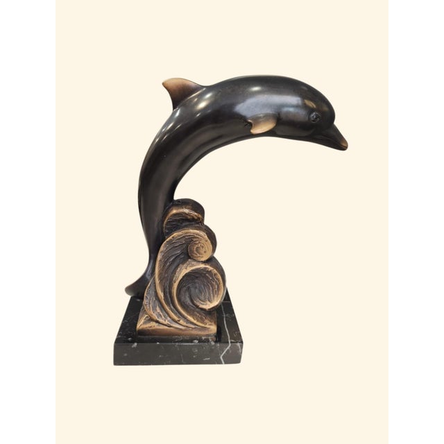 Dolphin sculpture made of solid bronze with a polished finish and details in golden patina that gently highlight its fluid...