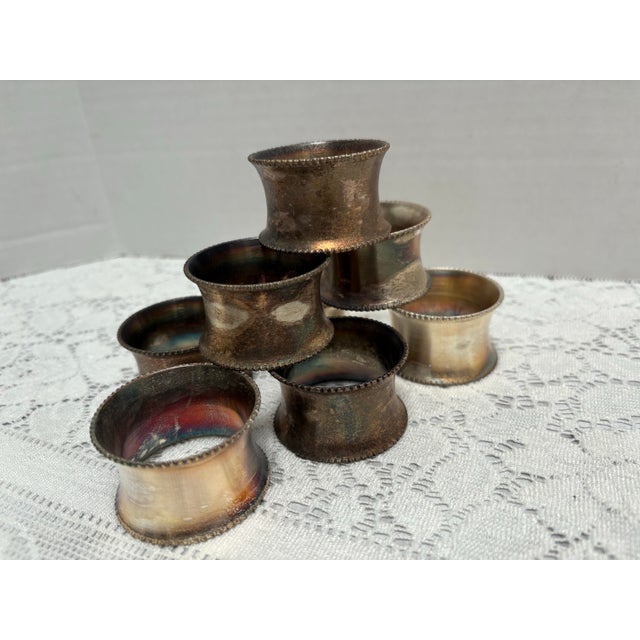 Vintage set of eight silver napkin rings with etched edges, iridescent patina from age and tarnished use. I haven’t...