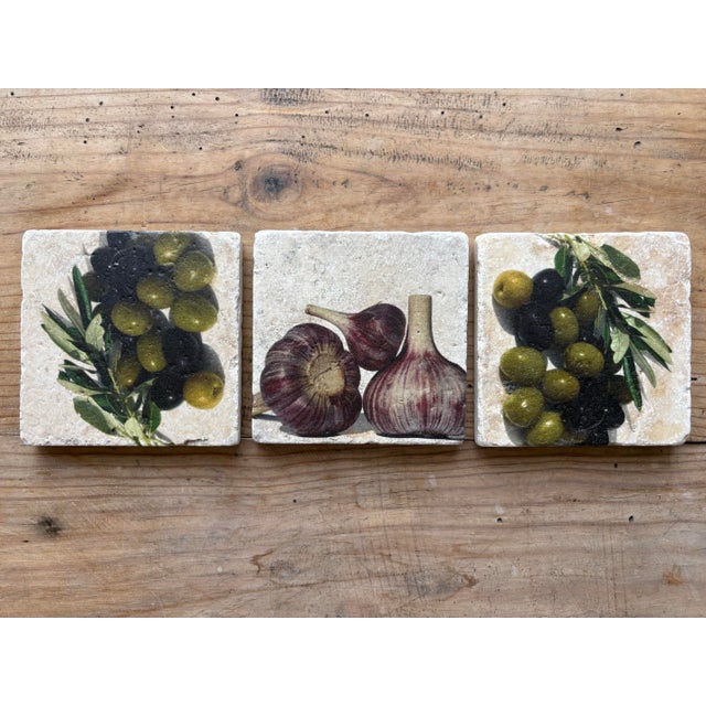 Charming set of three decorative travertine stone coasters featuring classic Mediterranean-inspired imagery of olives,...