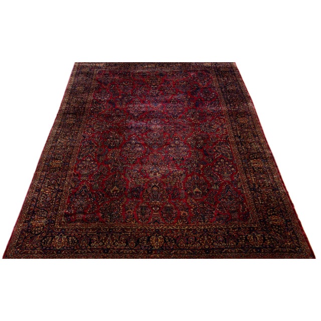 This luxurious antique Persian Sarouk rug is meticulously crafted by hand using fine wool. Its striking red field is...