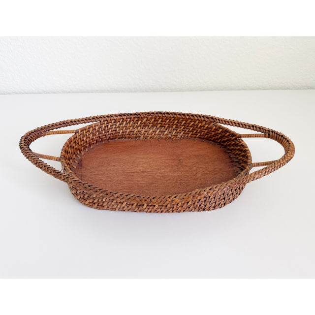 French style, early 20th century woven wicker oval tray in a mid-brown color. Features braided rattan rim, integrated...