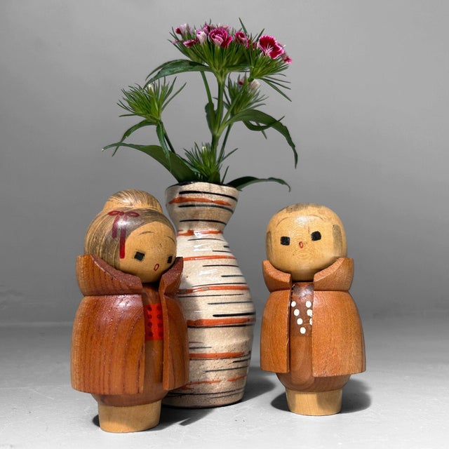 Adorable vintage pair of wooden kokeshi dolls with charming, hand-carved details. The figures feature expressive faces and...