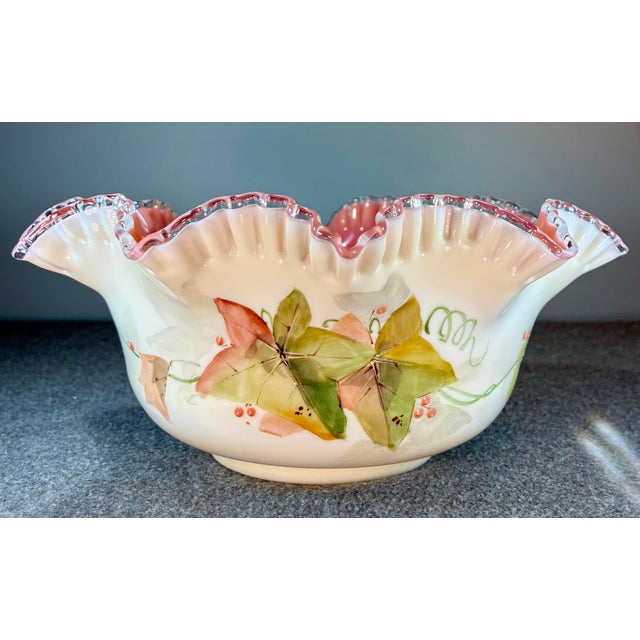 Cased art glass brides bawl/basket featuring hand painted leaves and bird design.. White exterior with a pink interior and...