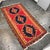 Design Plus Gallery presents a Vintage Handwoven Kilim Runner. This flatweave rug has a red field with three large navy...