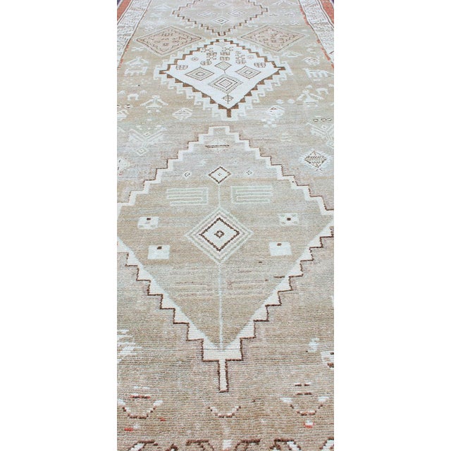 Antique Kurdish runner antique with tribal geometric medallions in soft green, brown, tape, salmon and orange-red border....