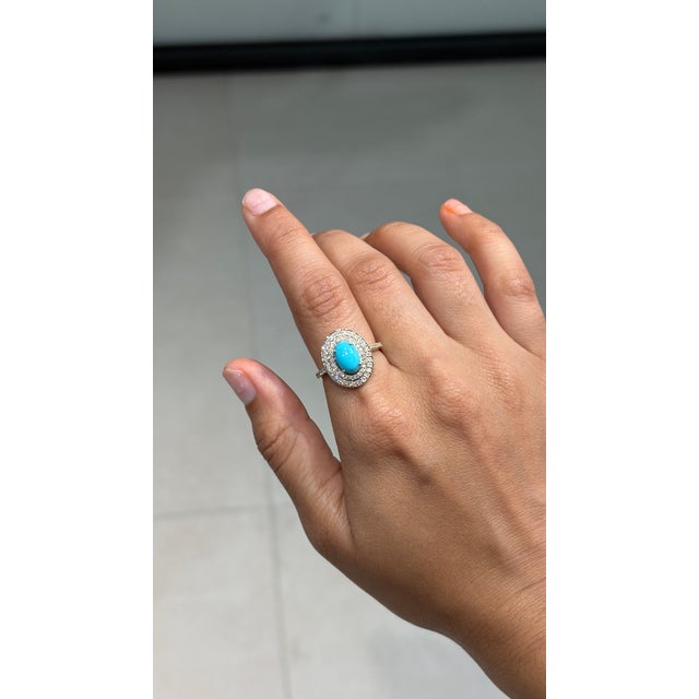 This Contemporary Double Halo Ring features a captivating 1.43 carat natural oval turquoise, set in 14k yellow gold. The...