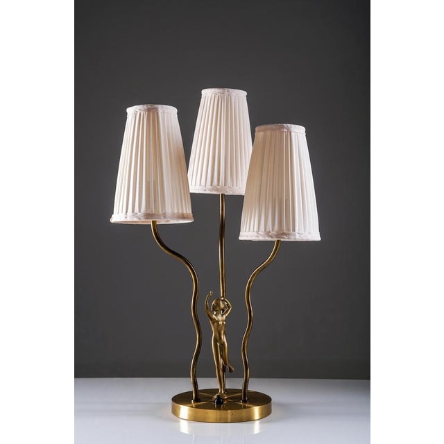 This Swedish Art Deco table lamp is crafted in brass and features an elegant sculptural form. The base is adorned with a...