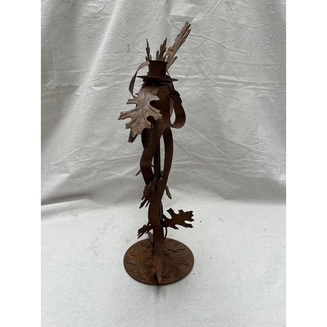 A single vintage tole candelabra featuring stylized oak leaves, ribbons, and acorns surrounding three taper candle holders...
