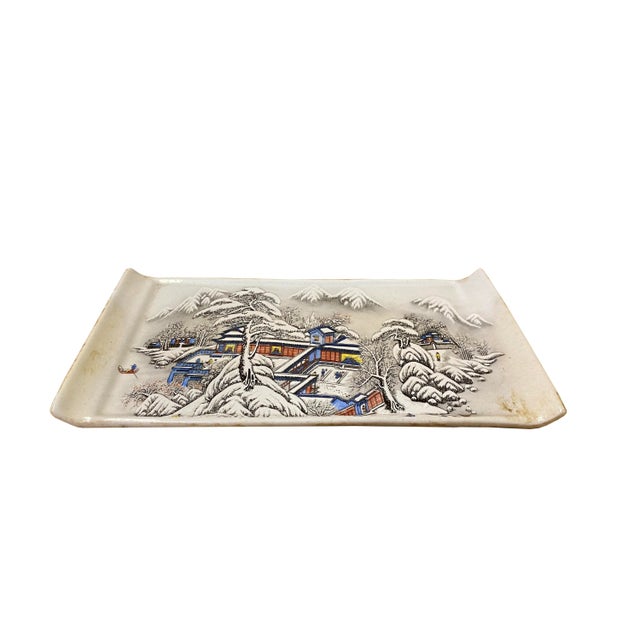 This is an oriental Chinese decorative plate with a distressed off white base and oriental snow trees house scenery...