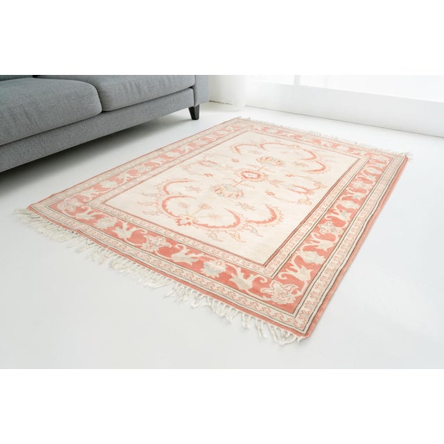 This is a vintage Turkish Oushak rug from the Mid 20th Century. The piece was hand-knotted.