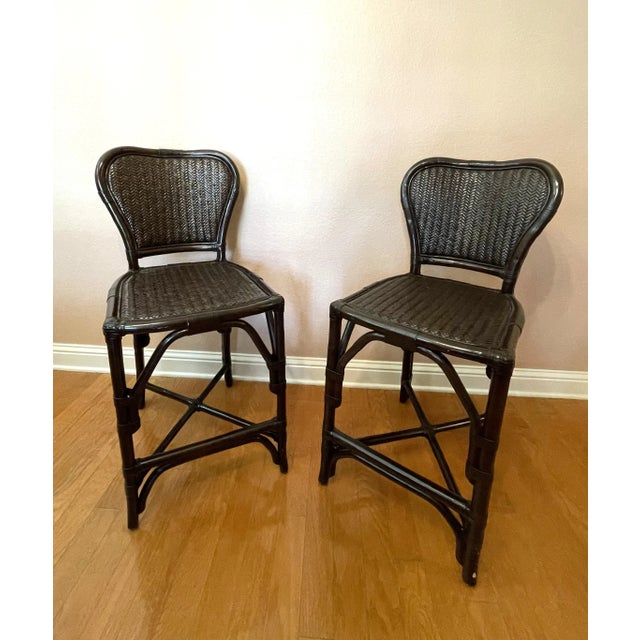 A pair of versatile black rattan and bamboo counter stools -- coordinates well in a traditional or contemporary interior....