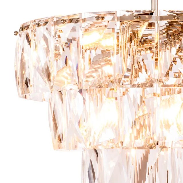 Sparkling rectangular crystals hang from different tiers, capturing and refracting light to create dramatic patterns on...