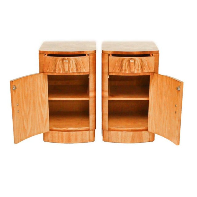 A pair of art deco bedside cabinets in figured walnut with original wooden handles. Drawer to top with shelved cabinet...