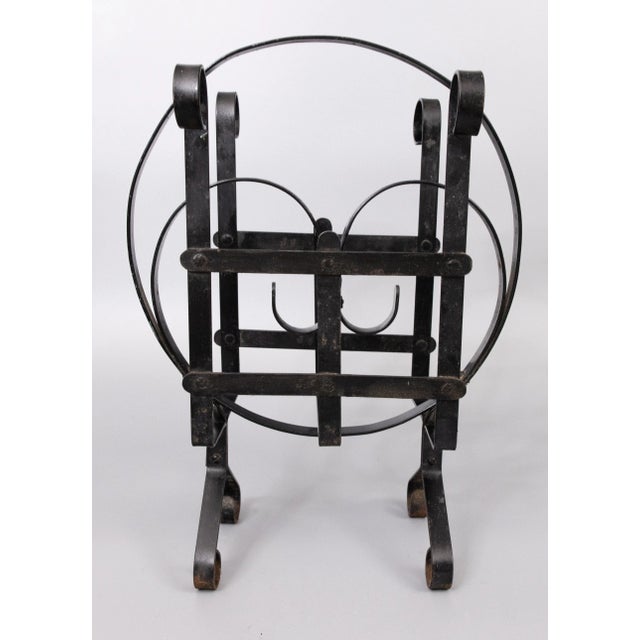 A charming French country black wrought iron magazine rack with stylized scrolls and lovely old paint and patina. It's...
